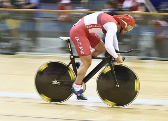 Cyclist in aerodynamic racing position during indoor track cycling race wearing team England cycling suit and helmet.