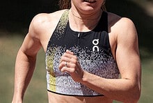 Female triathlete in athletic gear running outdoors during a triathlon event, showcasing endurance and fitness.