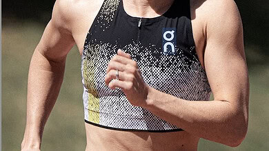European champion Jeanne Lehair running in a triathlon race, wearing a black and yellow sports top and shorts.